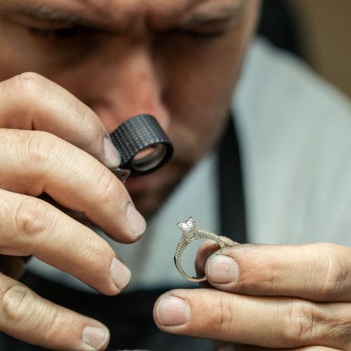 Jeweler examining and controlling quality of diamond ring in workshop